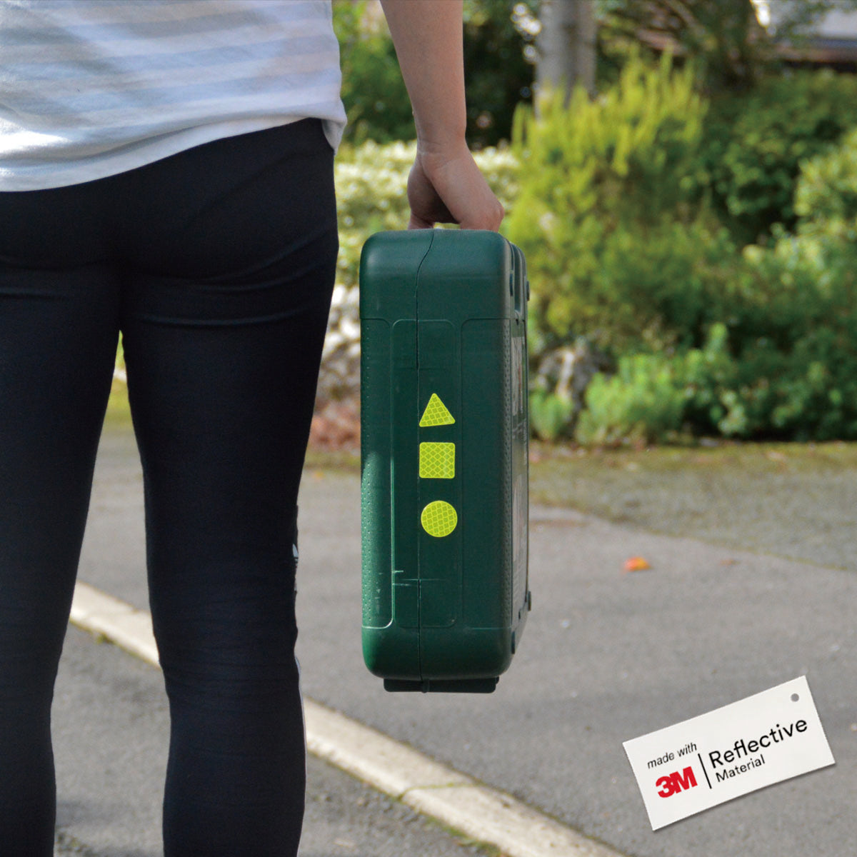 Person holding a tool box with 3 Yellow hi vis stickers on, triangle, square and circle.
