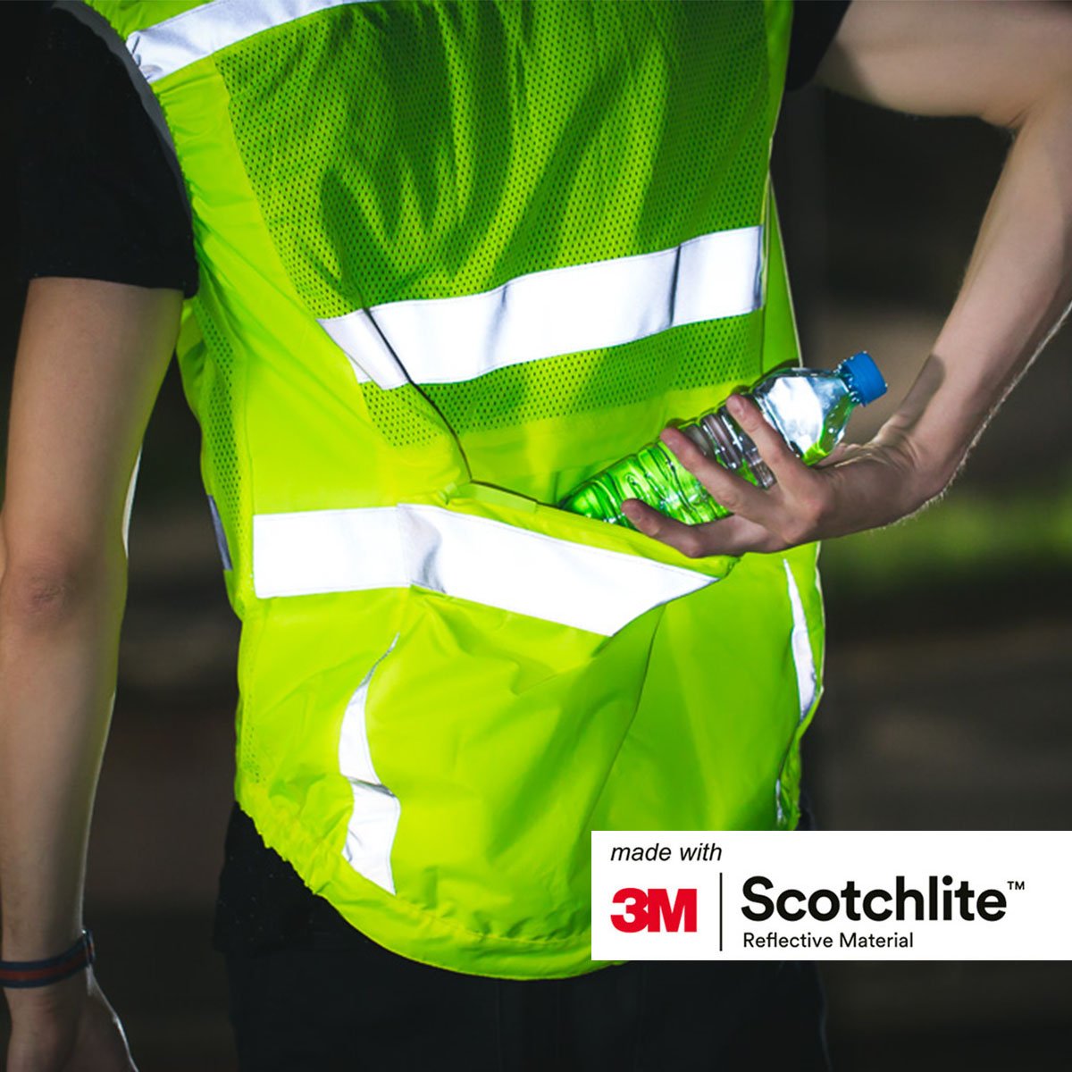 Man wearing Yellow reflective cycling vest, putting a bottle in the back pocket.