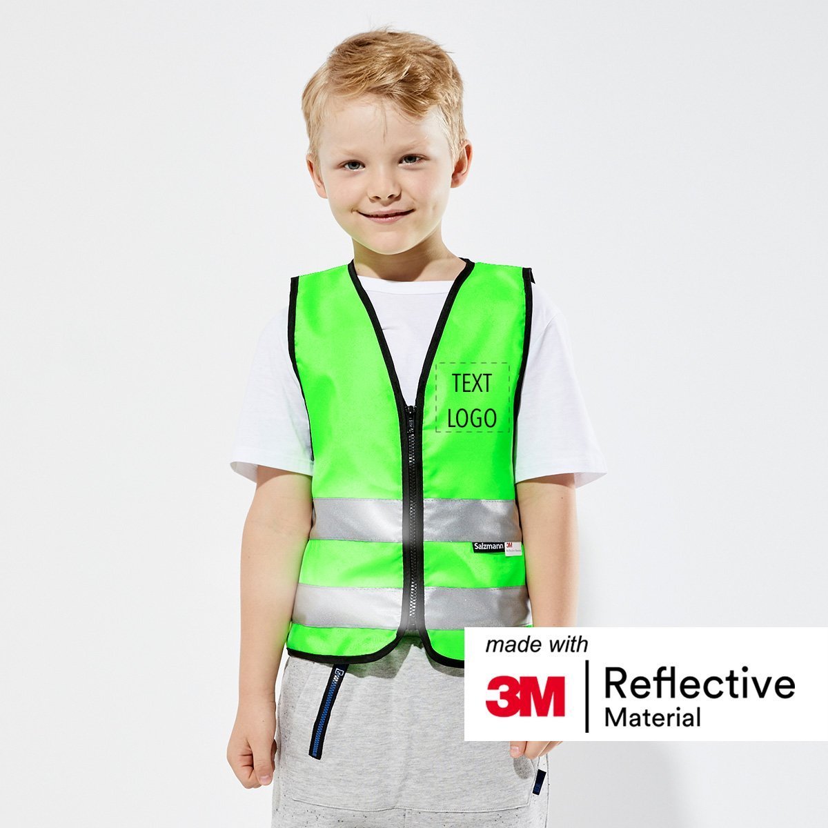 Boy stood smiling wearing a Green safety vest with "Text/Logo" on the front 