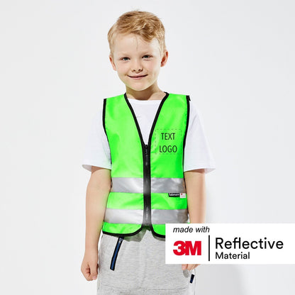 Boy stood smiling wearing a Green safety vest with "Text/Logo" on the front 